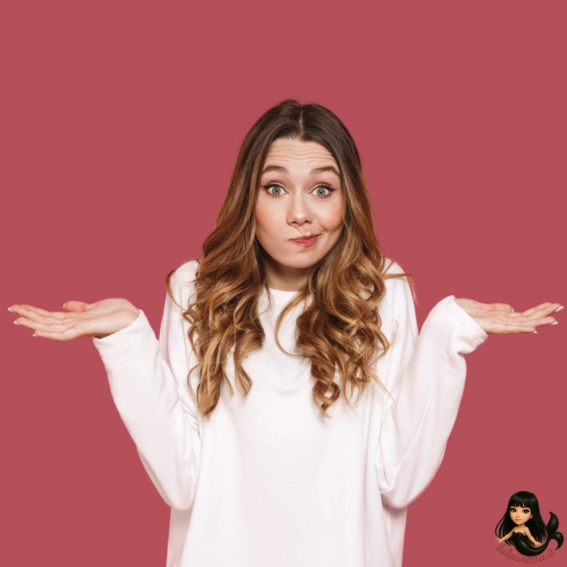 Conoscere persone online: dating e disabilità 1 Foto di una giovane donna con capelli biondo miele ondulati che fa spallucce con espressione perplessa, su uno sfondo malva scuro. Indossa una felpa bianca. In basso a destra, l'avatar chibi di Laura (Veus) del blog lalauretta.it.