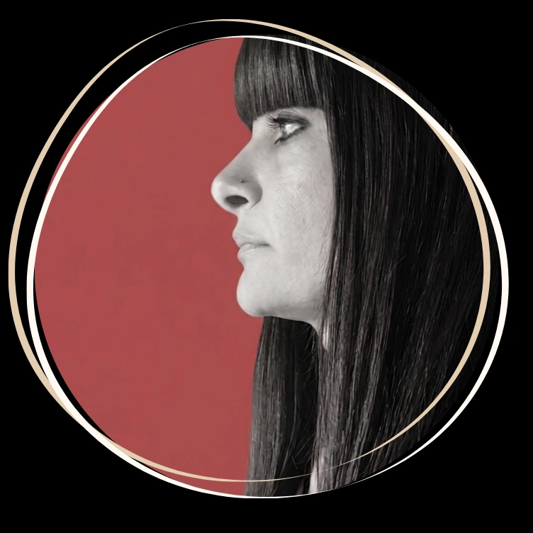 Home 11 Primo piano di profilo di Laura Mandaradoni in bianco e nero su sfondo rosso malva, con capelli lunghi neri, frangia dritta e piercing alla narice destra, racchiuso in una cornice circolare stilizzata per il blog La Lauretta.